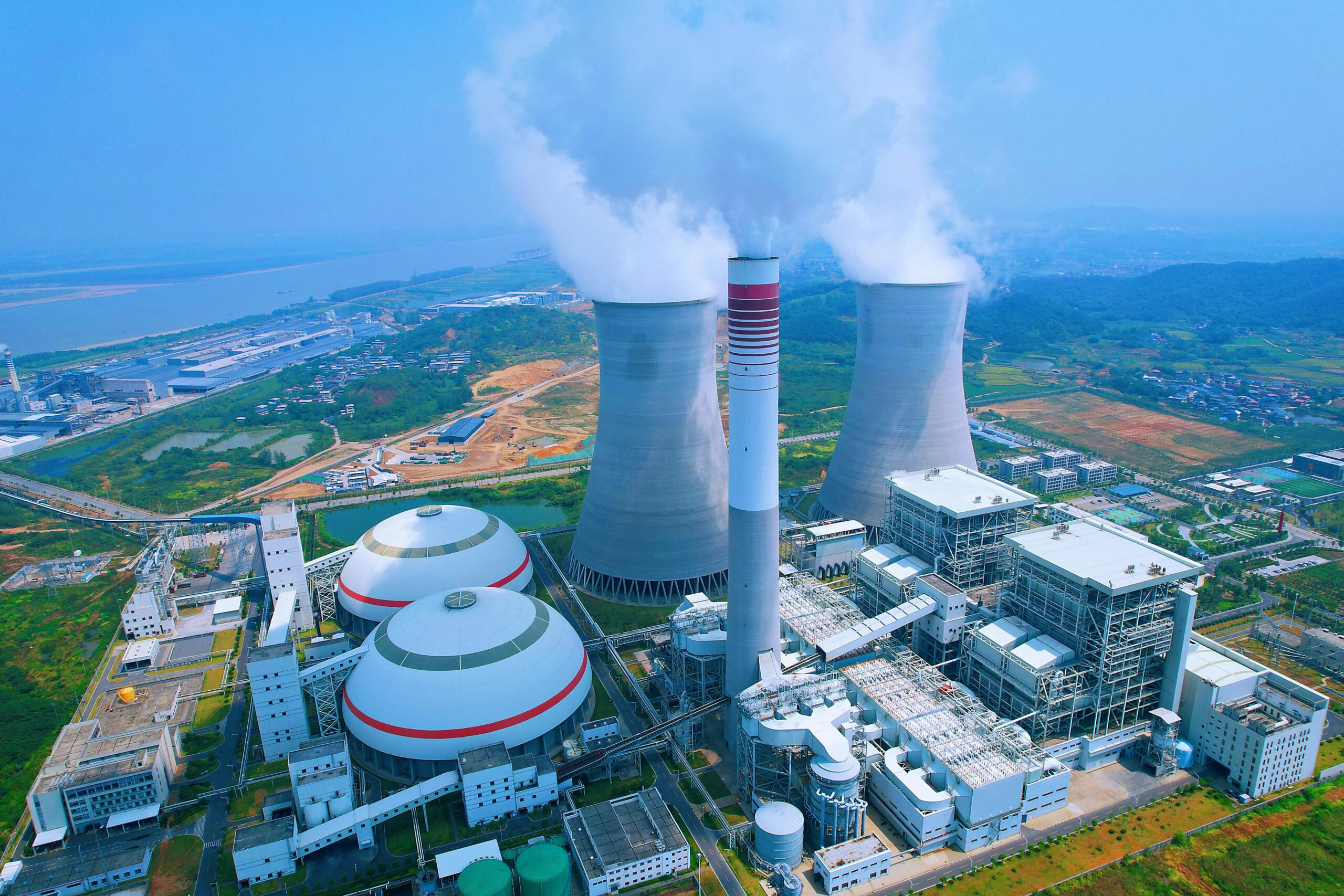Aerial shot of a power plant with cooling towers emitting steam in Jiujiang, China.