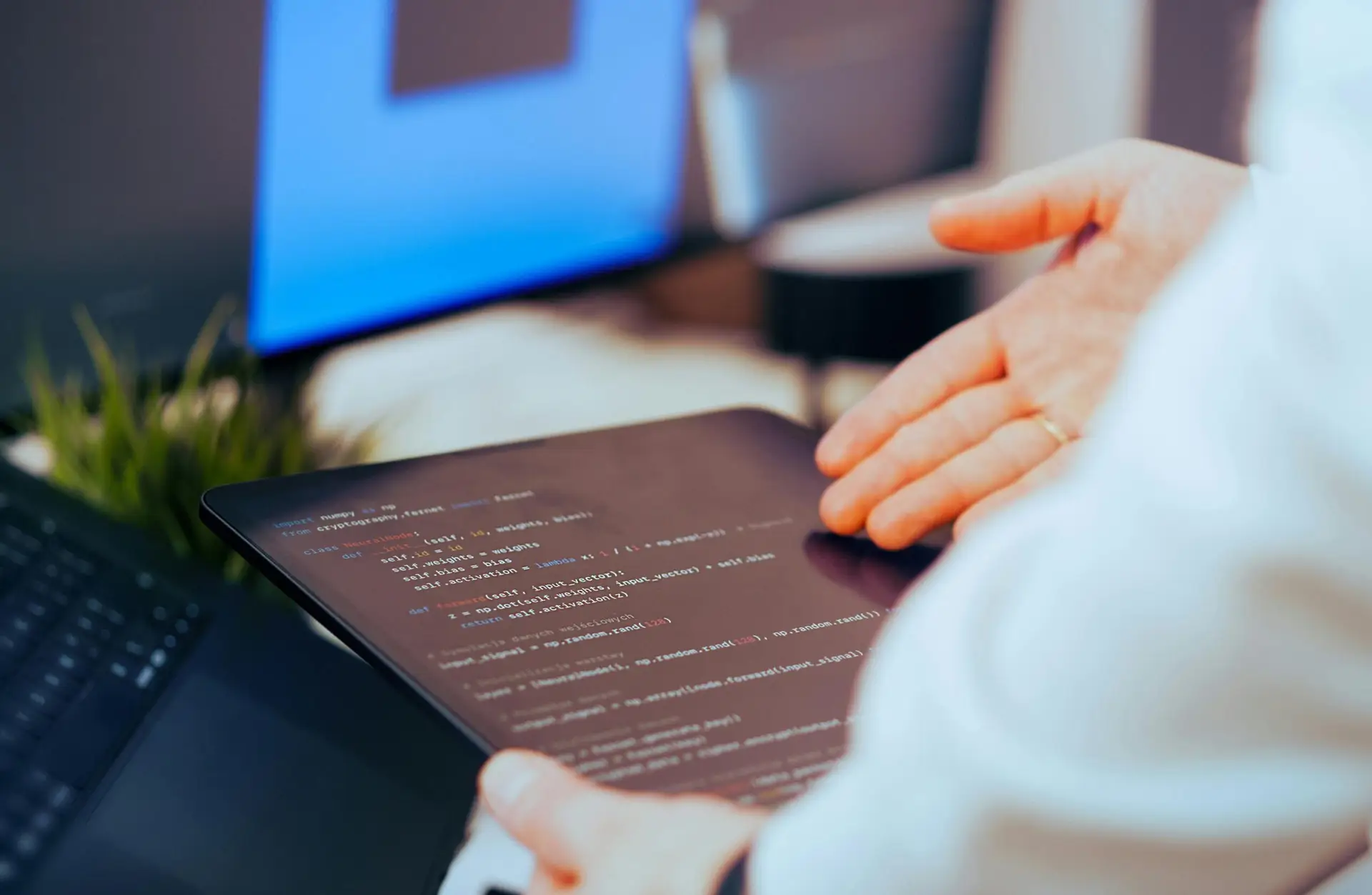 Software developer analyzing code on a tablet in a modern office workspace.